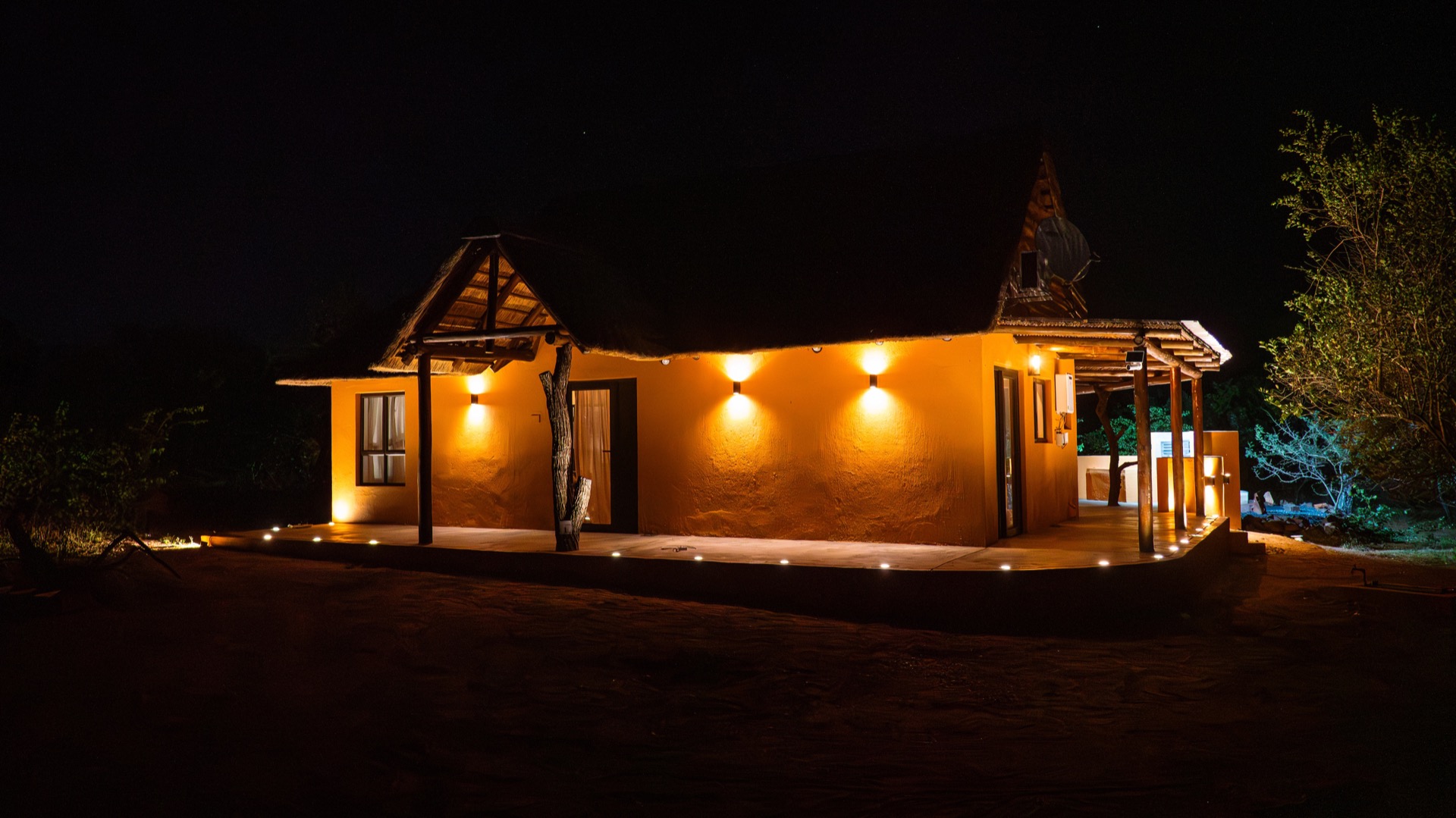 The villa lit up against the dark bush at night