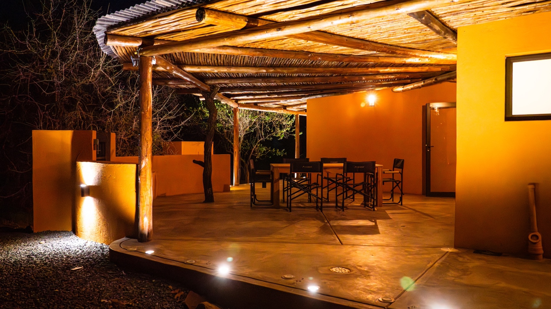 The covered patio and dining table lit warmly after dark