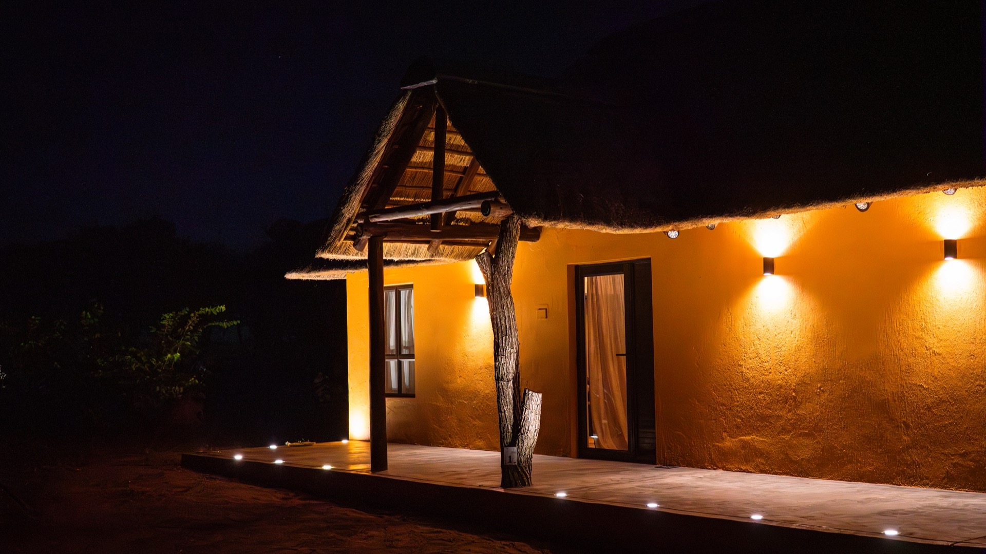 The front porch and entrance glowing under thatch at night