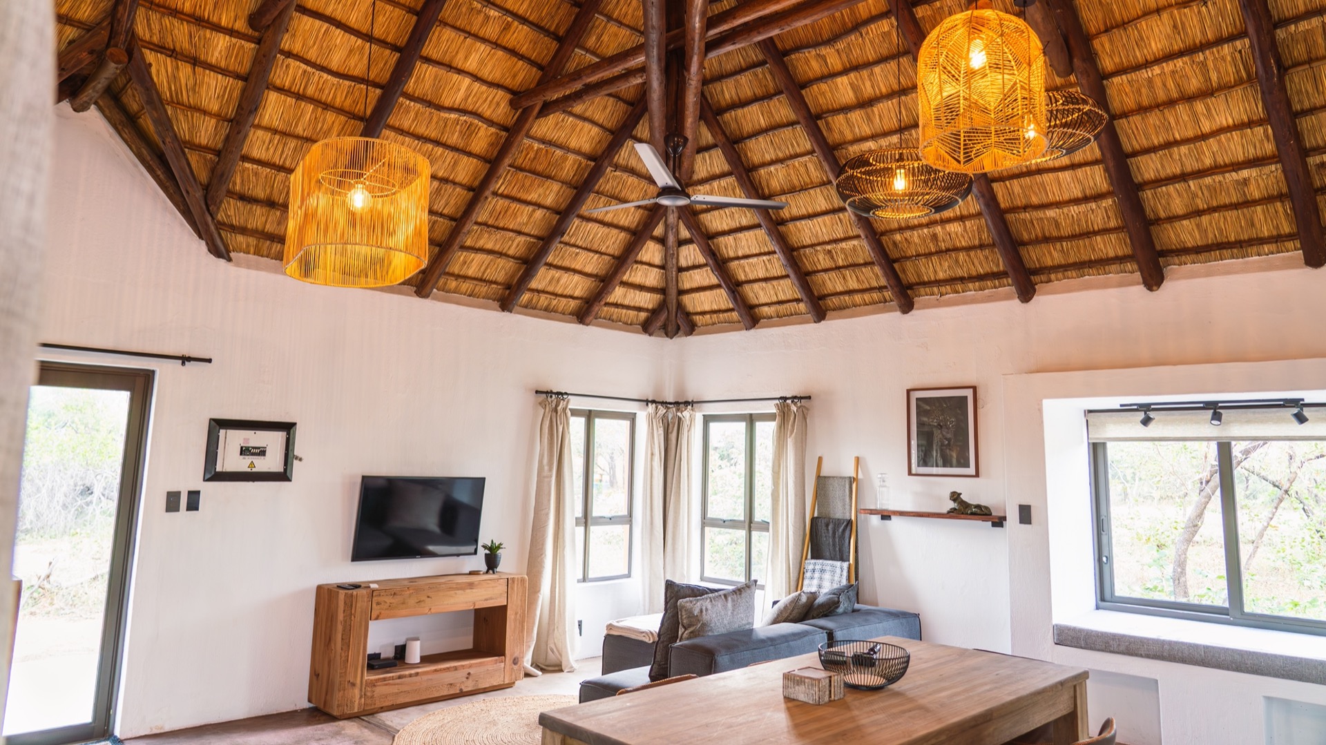 Open living and dining area under a soaring thatch roof